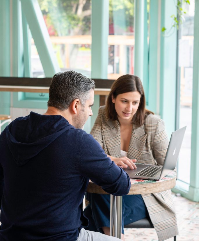 Two executives looking at a computer and having a discussion.